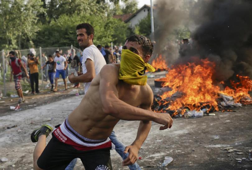 Migrants protest as Hungarian riot police fires tear gas and water cannon at the border crossing with Serbia in Roszke